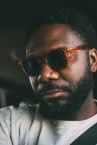 Close-up of young man wearing sunglasses against black background