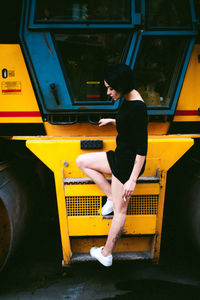 Side view of young woman standing on vehicle step