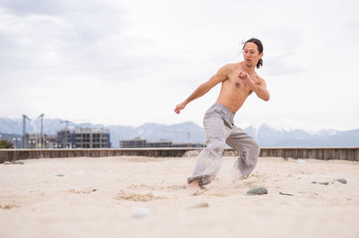 Full length of woman exercising at beach