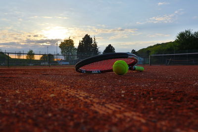 Tennis racket on court against sky during sunset