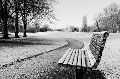 Empty bench in park against sky