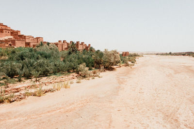 Dirt road amidst buildings against clear sky