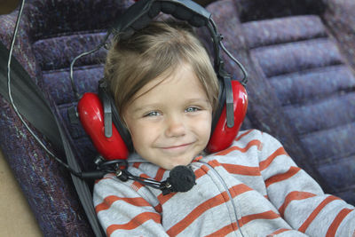 Close-up portrait of cute girl wearing headphones sitting in air vehicle