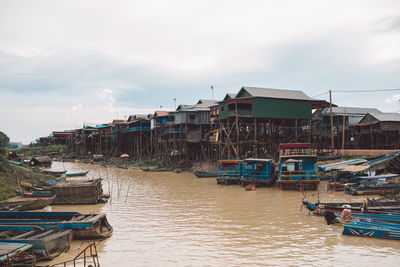 Boats moored at harbor by buildings against sky