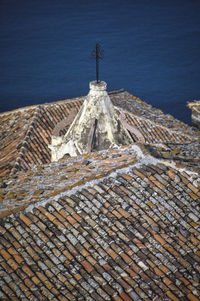 Tilt image of roof and building by sea against sky