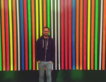 Portrait of young man standing against colorful patterned wall