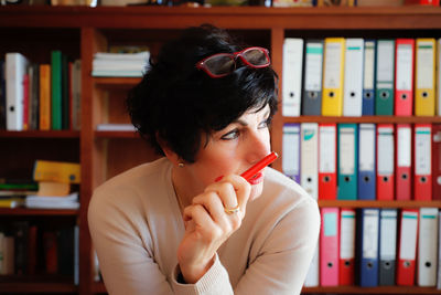 Woman sitting against book at library