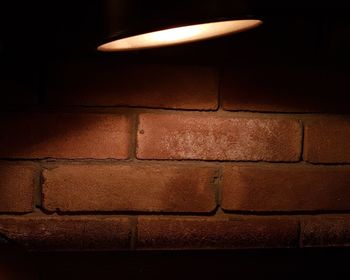 Close-up of illuminated light bulb against wall