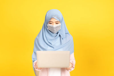 Portrait of a teenage girl against yellow background