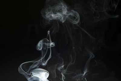 Close-up of emitting smoke against black background