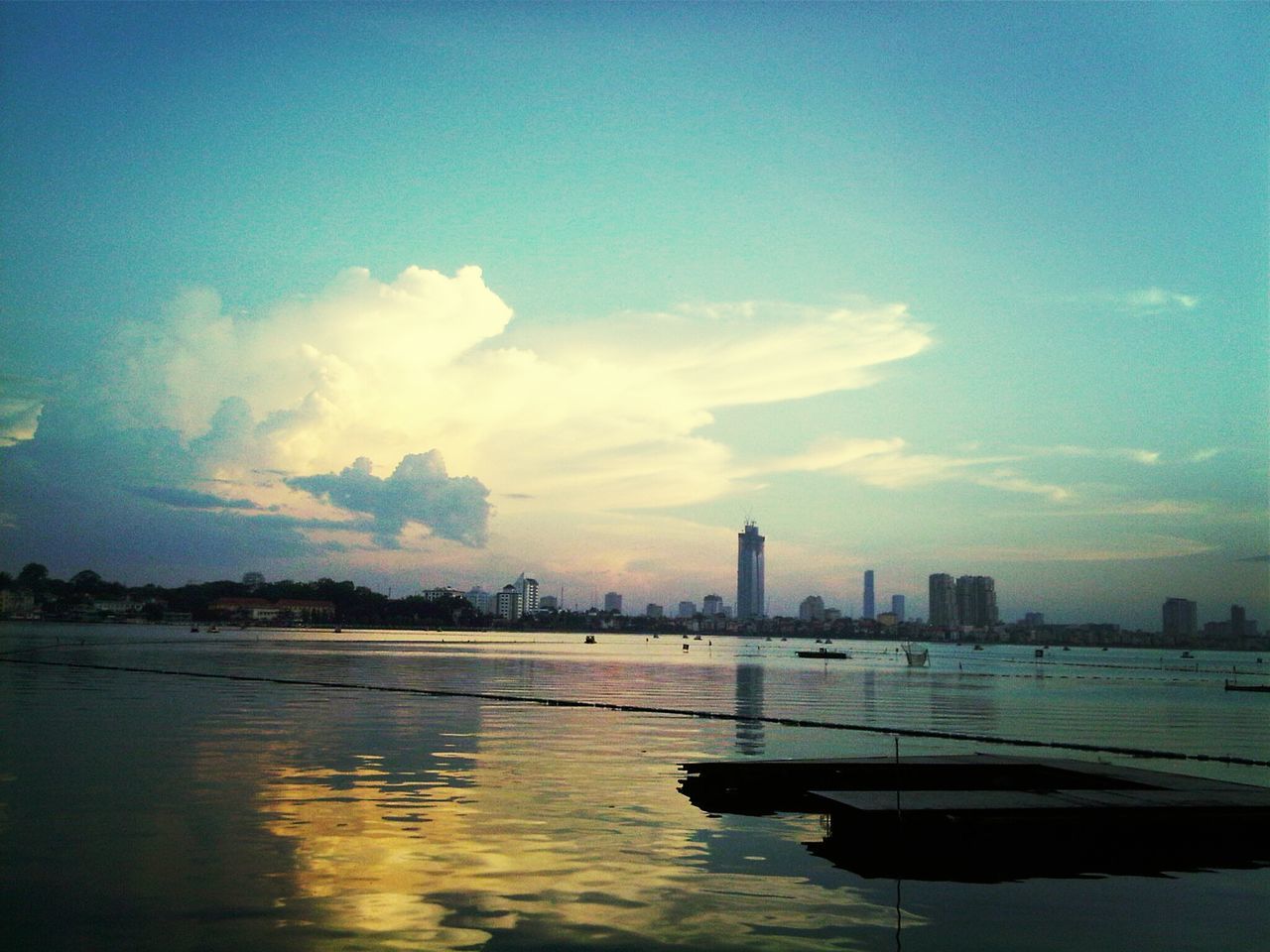 water, waterfront, sky, building exterior, city, built structure, sea, architecture, nautical vessel, cityscape, cloud - sky, scenics, sunset, cloud, blue, tranquility, boat, skyscraper, nature, river