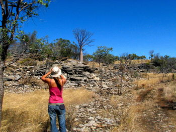 Rear view of woman standing on landscape against clear blue sky