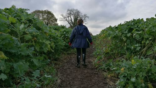 Rear view of a girl on agricultural field against cloudy sky