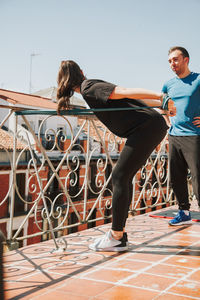 A couple doing training with rubber resistance band on their fooftop