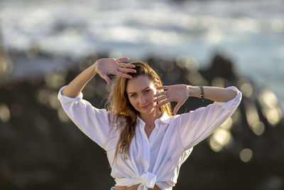 Portrait of young woman with arms crossed standing outdoors