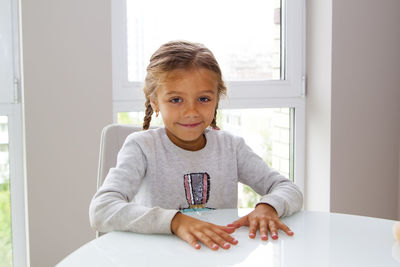 Portrait of girl holding table at home