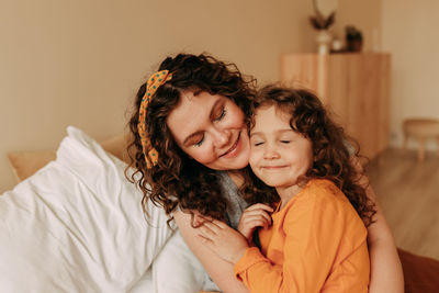 Portrait of happy smiling curly-haired mom and daughter on mother's day at home