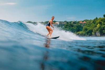 Side view of man surfing in sea against sky