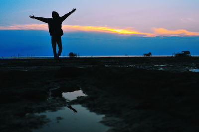 Silhouette man standing on beach against sky during sunset