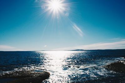 Scenic view of sea against blue sky on sunny day