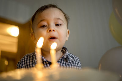 Cute boy blowing candles and celebrating his birthday at home