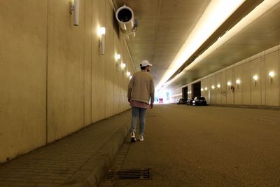 Rear view of man walking on illuminated corridor