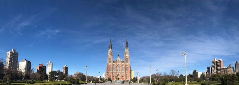 Panoramic view of buildings in city against blue sky