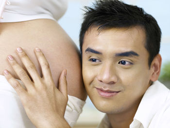 Man listening to belly of pregnant woman at home