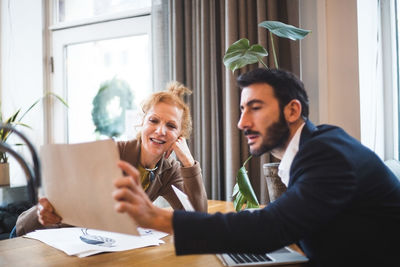 Smiling female illustrator showing drawing to male professional at office