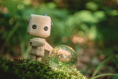 Environment concept, a wooden robot, crystal ball, on moss in the forest, environmental protection.