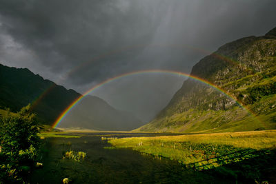 Scenic view of rainbow over mountains and river