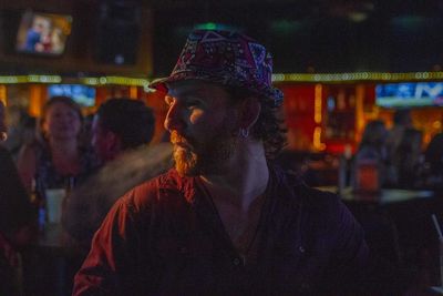 Full length portrait of young man standing in city at night