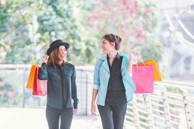 Happy friends with shopping bags walking on elevated walkway