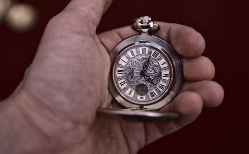 Cropped hand holding pocket watch