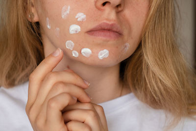 Unrecognizable woman applies makeup, cream serum cure for acne on face. close-up acne on woman's