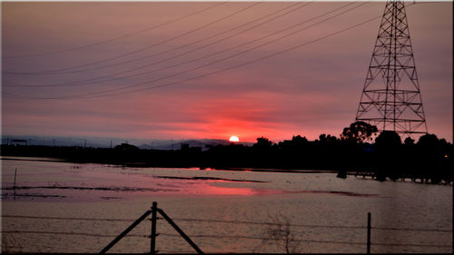 Silhouette bridge over calm river at sunset