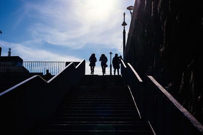 Low angle view of silhouette people on staircase against sky