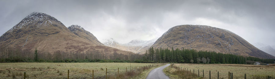 Panoramic view of road amidst field against sky