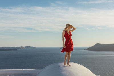 Woman wearing hat standing on built structure against sky