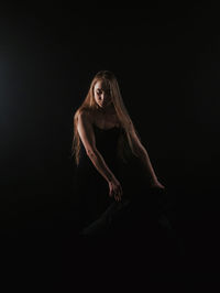 Woman dancing against black background