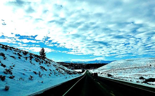 Road leading towards snowcapped mountain against sky