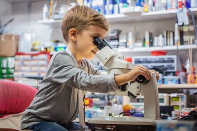 Side view of boy looking through microscope