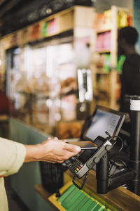 Hand of young male customer paying through smart phone at store checkout