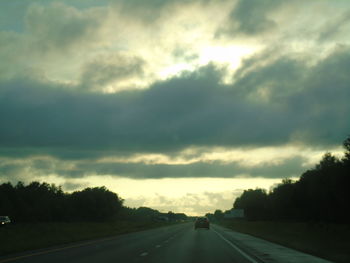 Country road against cloudy sky