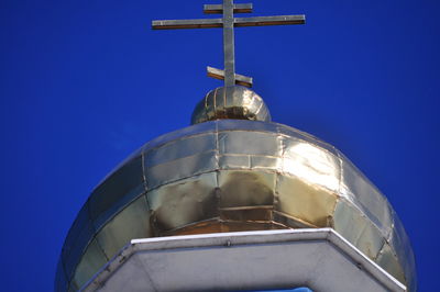 Low angle view of cross on building against clear blue sky