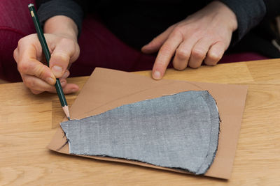 Midsection of person holding paper with text on table