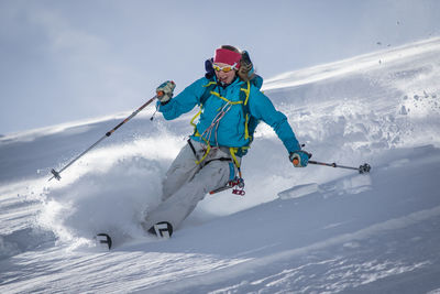 Young woman skiing on snowfield against sky