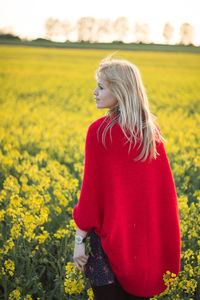 Rear view of young woman looking away while standing on field