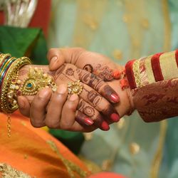 Cropped image of bride and bridegroom holding hands during wedding ceremony