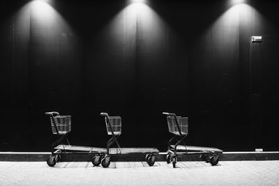 Empty chairs against wall at night